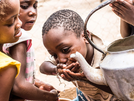 Suppenküche in Katutura, Namibia - Ein Kind trinkt Wasser aus einer Kanne